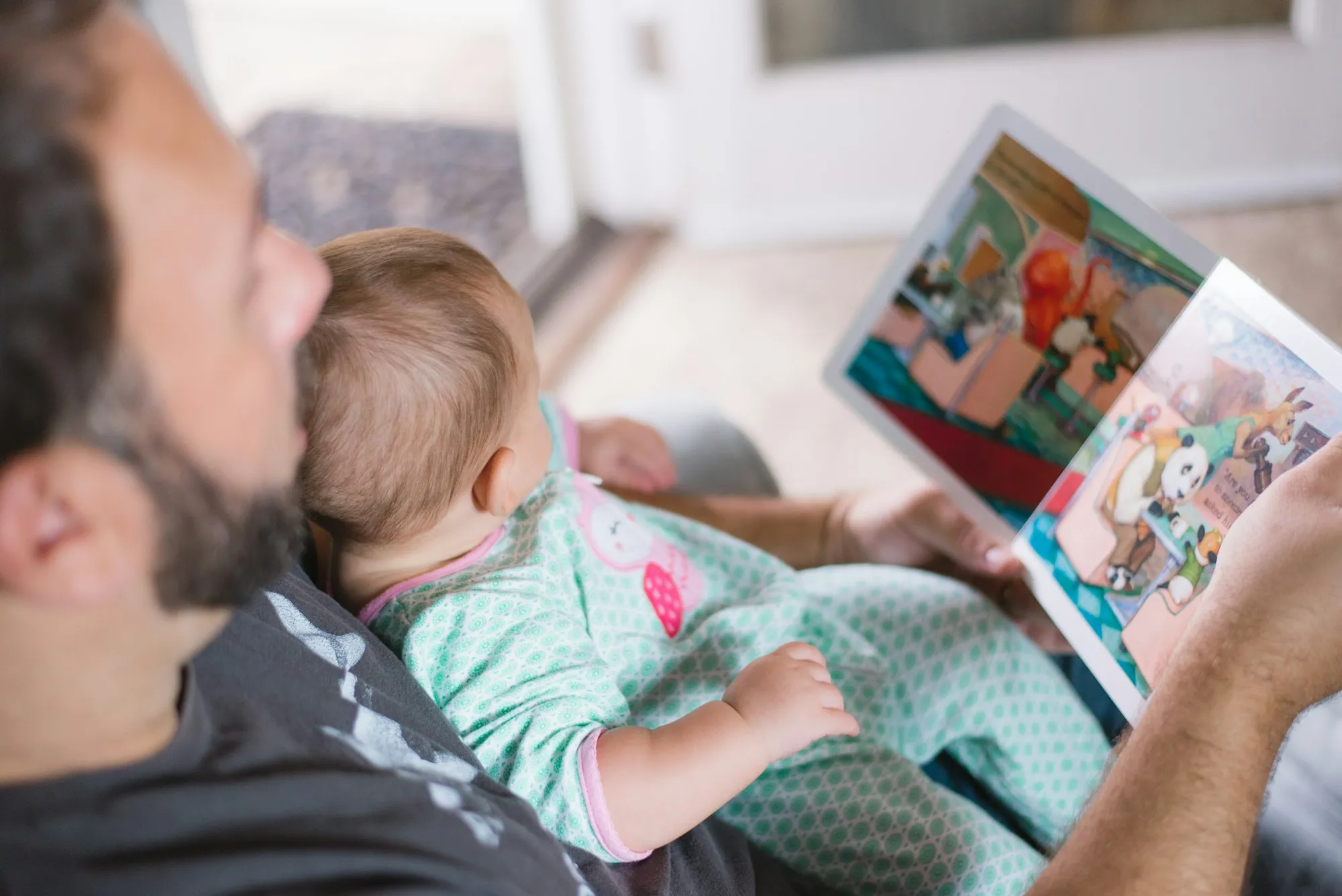 Dad reading a picture book to the baby lying on his chest