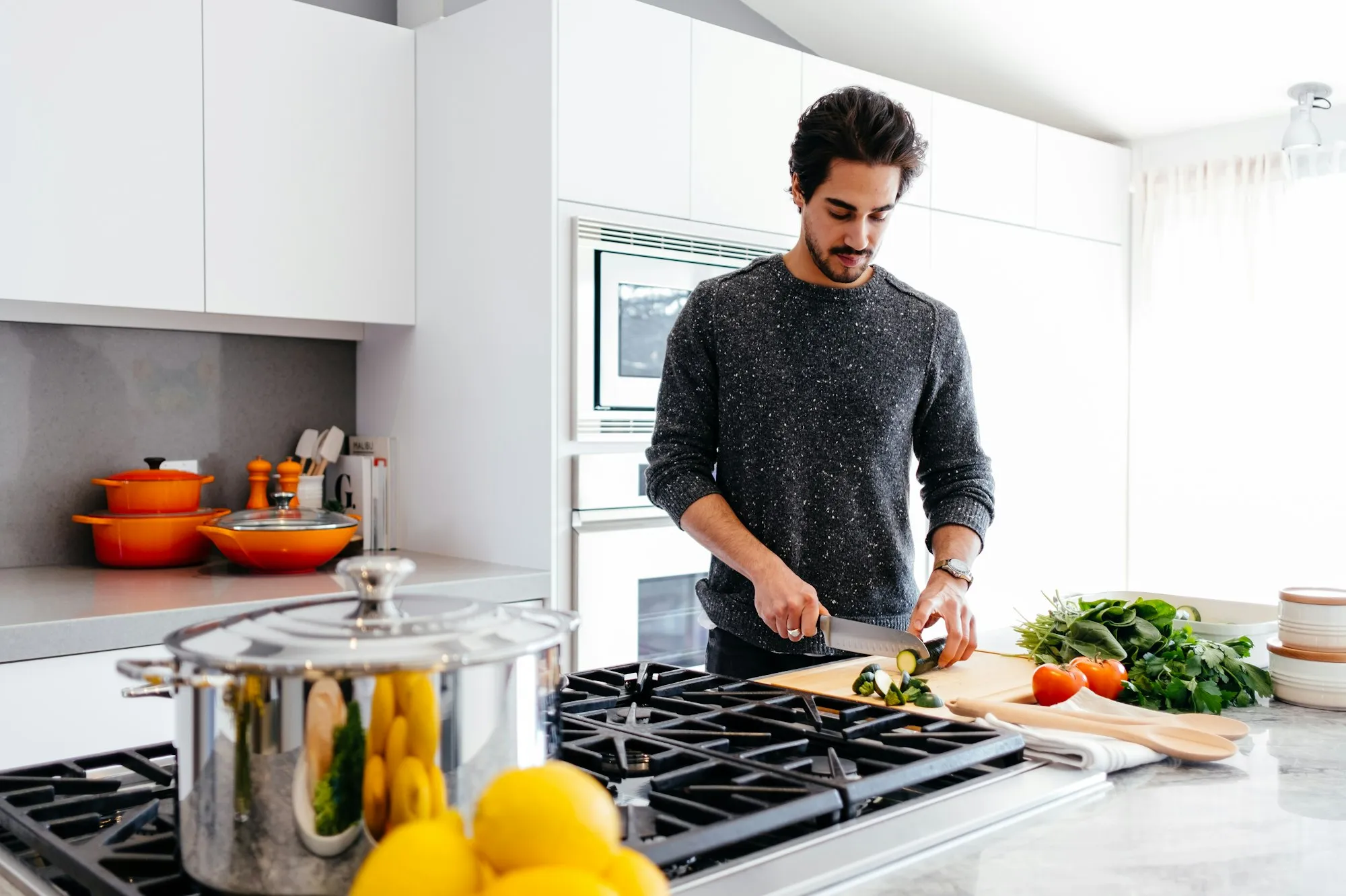 Man chopping vegetables at a kitchen counter next to a stove