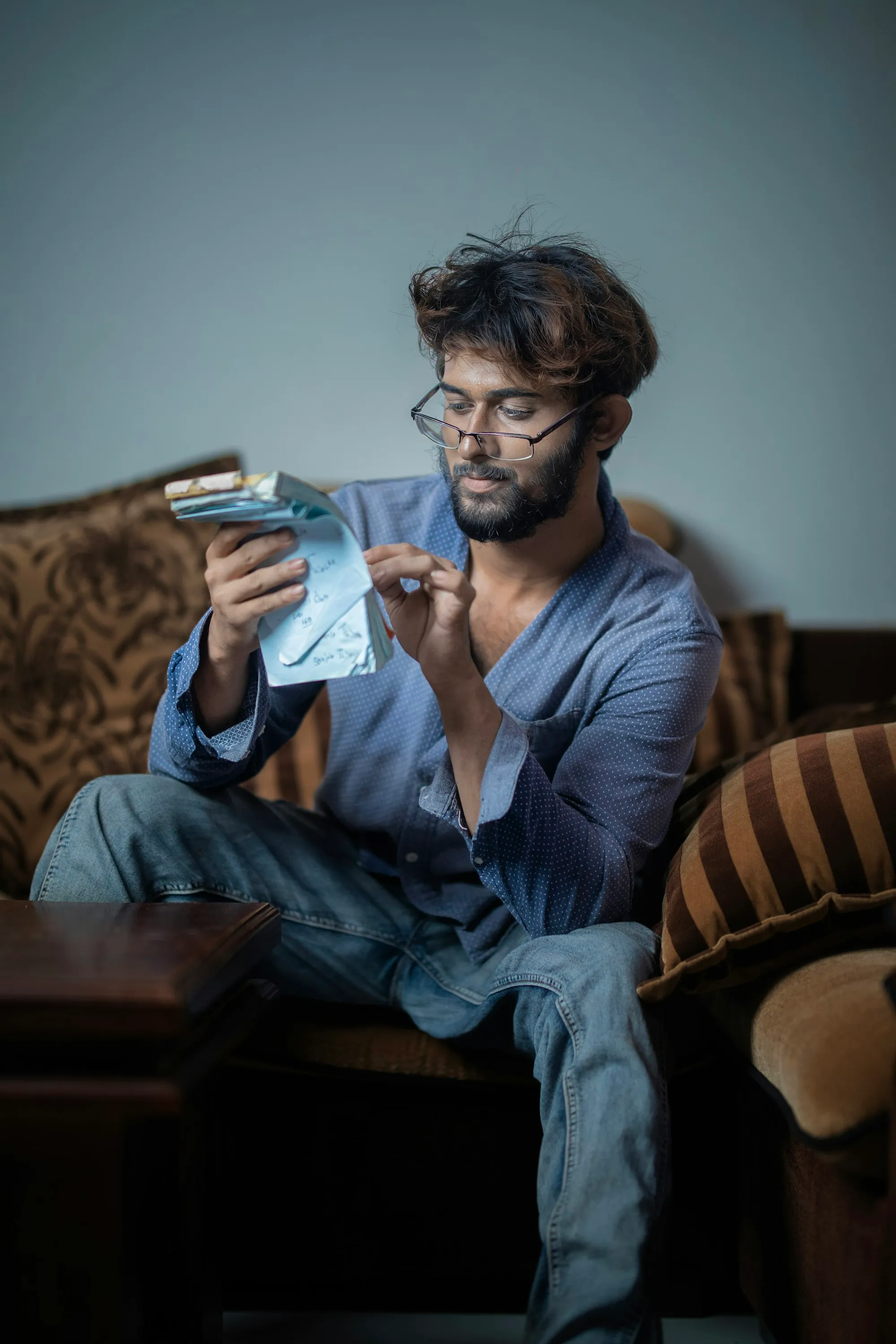 Man on a sofa counting a small stack of cash